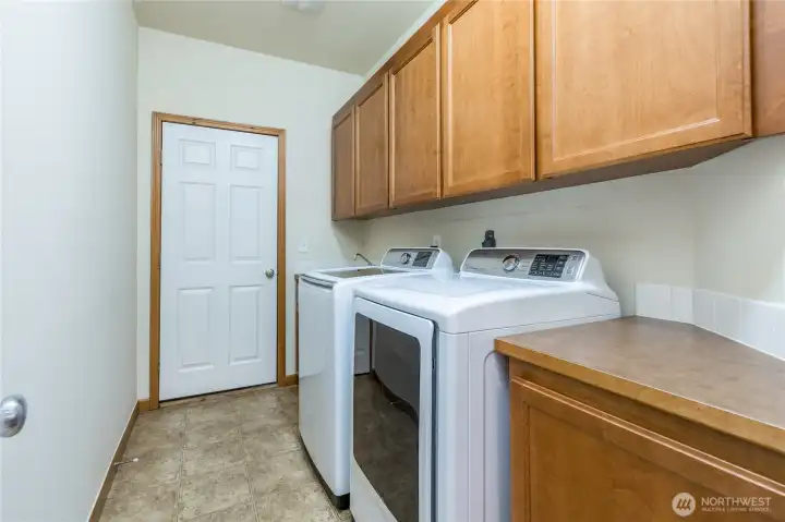 Laundry room includes generous cabinetry, utility sink, and direct access to the 3-car garage.