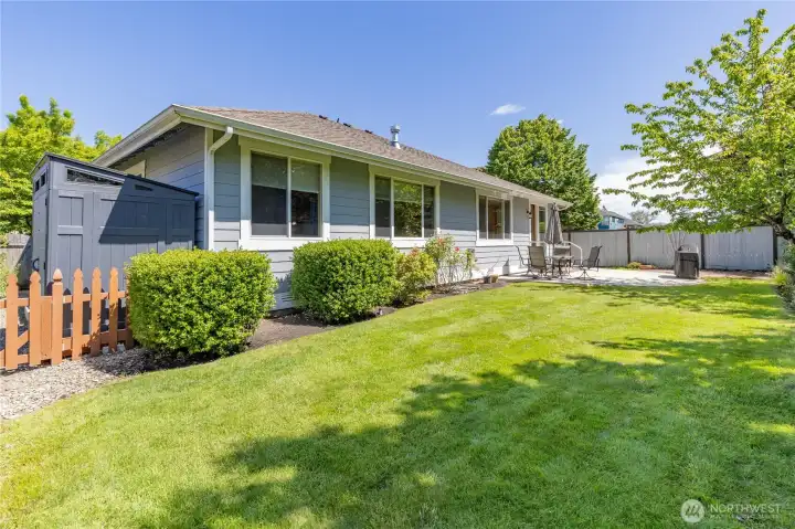 Beautifully maintained yard includes a practical garden shed for additional storage.