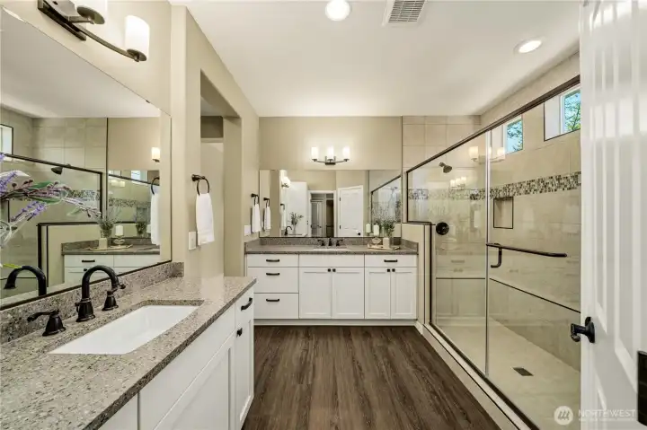 Highly upgraded primary bath offers two vanities with Quartz counters, beautiful hardware, fully tiled shower with dual heads & an upgraded enclosure door, waterproof wide plank flooring.