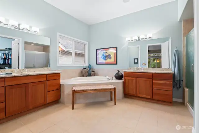 Elegant primary bath with dual vanities and undermount sinks, soaking tub, step-in shower and a separate water closet.