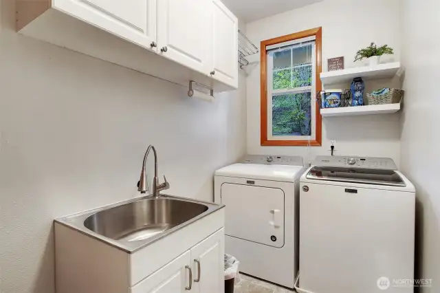 Laundry room off of garage, with cabinets for storage.