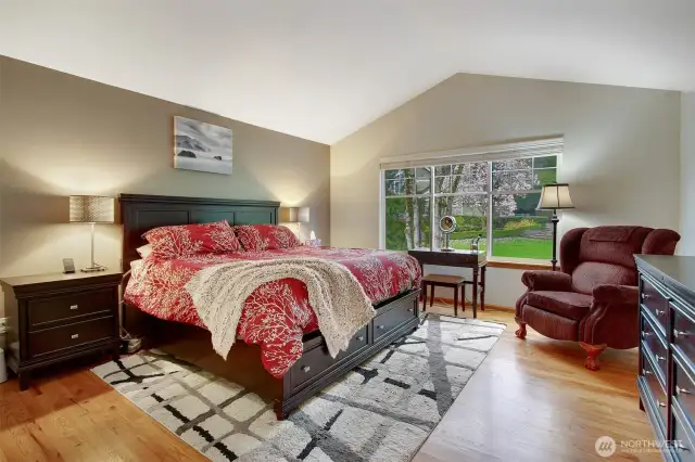 Primary bedroom w/ vaulted ceiling, and hardwood floors.