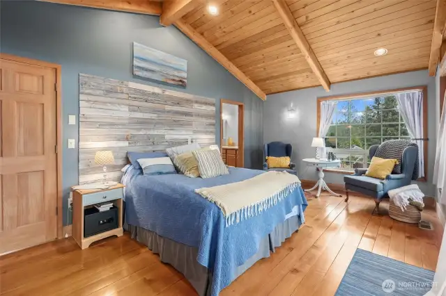 Primary suite with hardwood floors, gorgeous wood vaulted ceilings, and custom headboard.