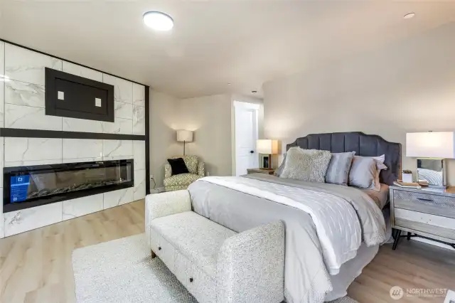 Primary bedroom with it's own cozy fireplace + a view of the lake.