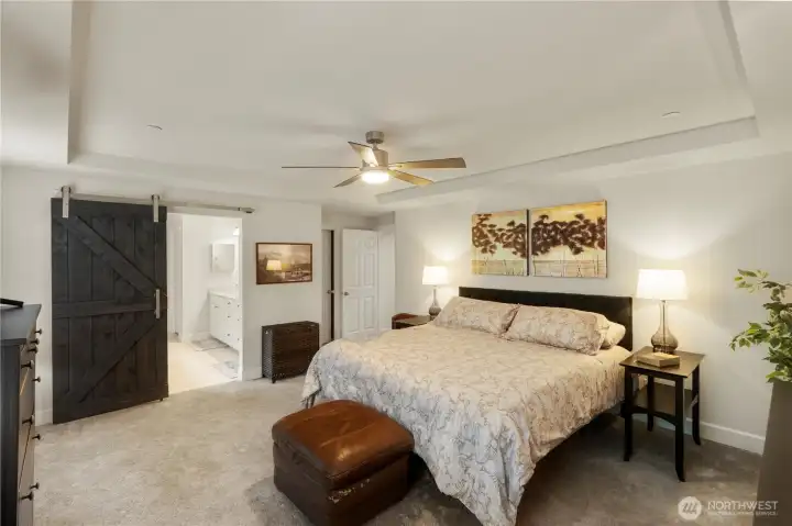 Spacious Primary bedroom with barn style door leading to the bathroom.