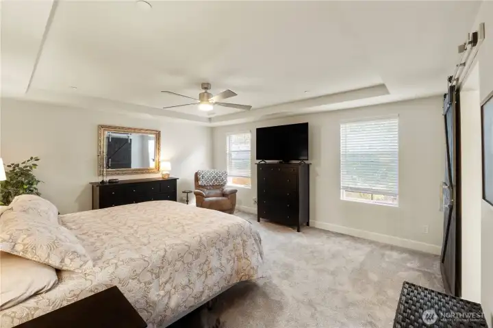 Large primary bedroom with coffered ceiling and fan.