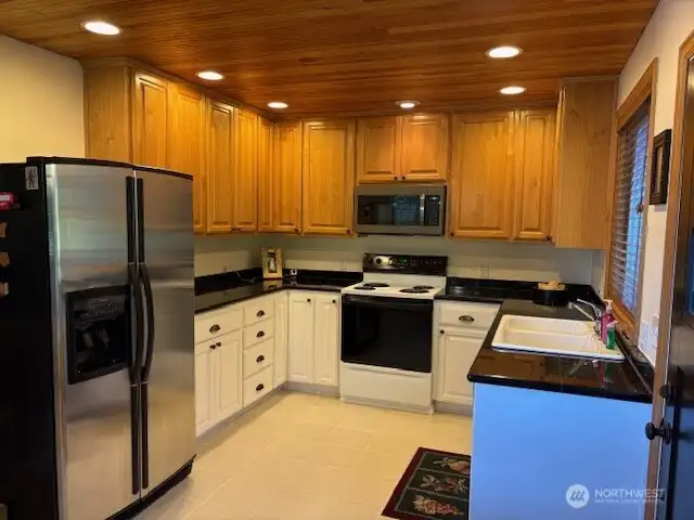 Updated kitchen with granite tile counters, Alder cabinetry and tile flooring.