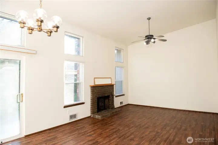 Vacant gorgeous living room with vaulted ceilings, large windows & ceiling fan!