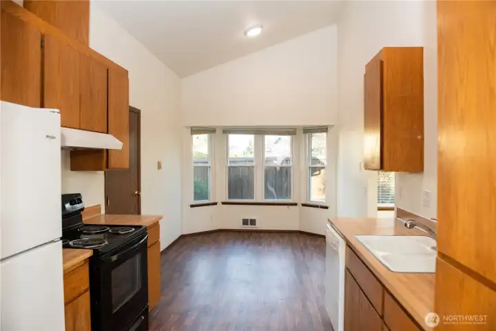 Vacant kitchen & dining room with bay window.