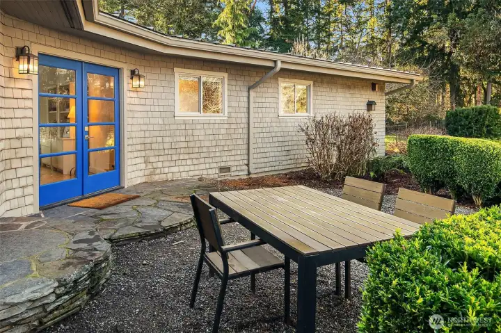 Closer look at the main entrance off the gravel garden, with French doors and flagstones.