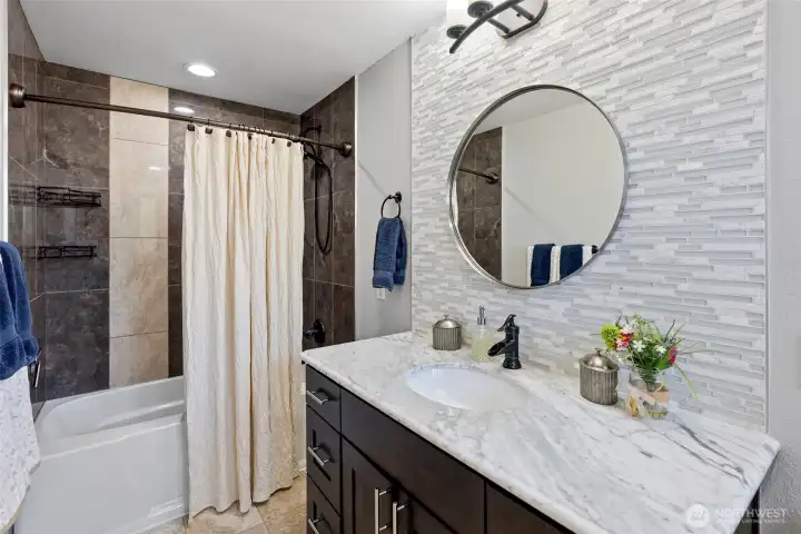 The updated Primary bath with marble countertops and tiled bath. Private and included in this en suite The updated Primary bath with marble countertops and tiled bath. Private and included in this en suite