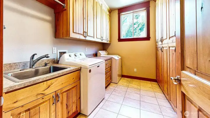 laundry room on the left. there is plenty of counterspace, cabinets and a deep laundry sink.
