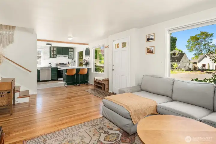 Spacious living room and modern kitchen with gorgeous hardwood oak floors and tall, south-facing windows that bring in lots of natural light