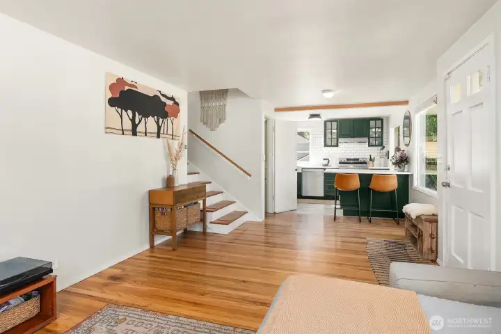 Spacious living room and modern kitchen with gorgeous hardwood oak floors and tall, south-facing windows that bring in lots of natural light