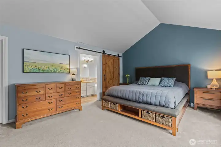 Relax and unwind in the spacious primary suite featuring vaulted ceilings and serene views.