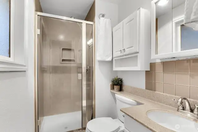 Private Primary bath with solid surface shower and counter, and good storage.