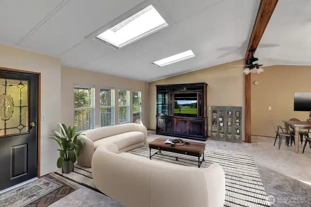 Beamed ceiling with sky lights in the open and light living room area. Room for sofas, recliners, entertainment center and more.