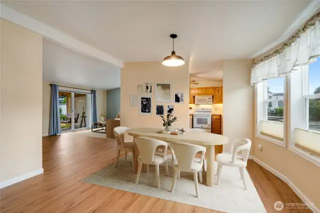 Open dining and living areas with NEW LVP flooring and easy flow to backyard covered patio. (Virtually staged)
