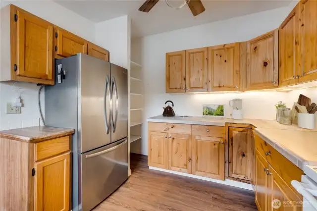 Kitchen offers stainless fridge, generous cabinetry, and NEW LVP flooring. (Virtually staged)