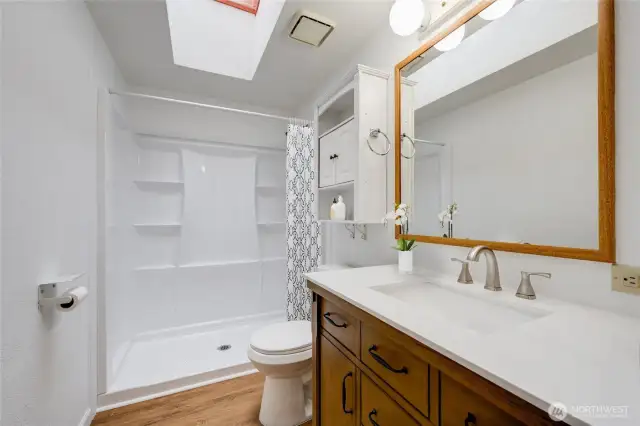 Beautifully updated guest bath with skylight and NEW: walk-in shower, vanity, toilet & LVP flooring! (Virtually staged)