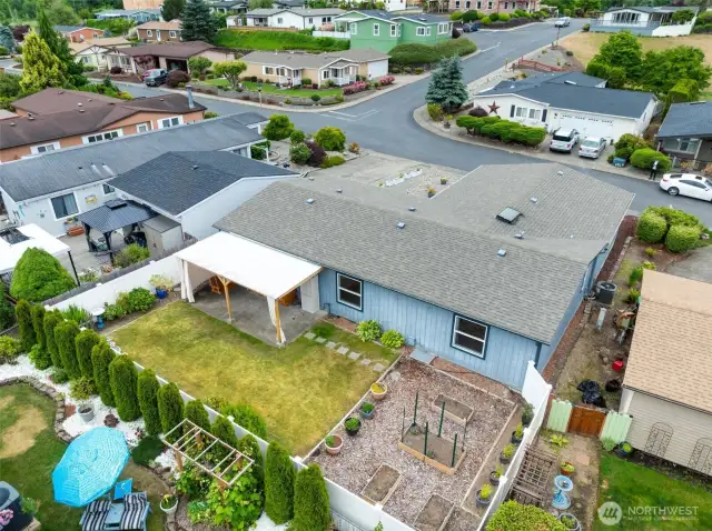 Overhead look at the home, covered patio, raised garden beds, and peaceful setting.