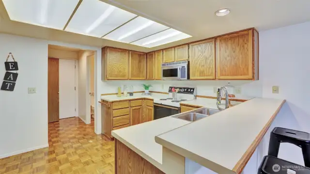 This kitchen showcases beautiful oakwood cabinets that add warmth and character, paired with expansive countertop space perfect for meal preparation, serving, and gathering