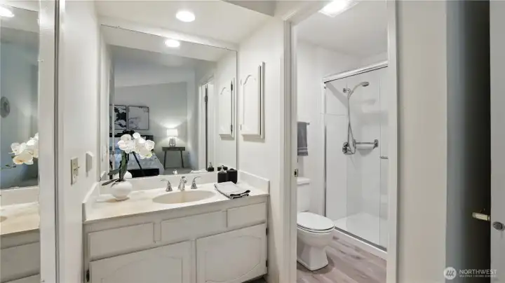 Nestled inside the primary bedroom and refreshed with all new recessed lighting, this ensuite bathroom features sleek countertops, abundant mirrors, and a separate toilet and walk-in shower, combining style and functionality
