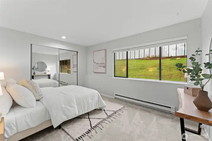 Generously sized primary bedroom with plush carpeting and a soothing neutral palette. Mirrored closet doors reflect natural light and enhance the open feel, while the well-proportioned layout easily accommodates a king-size bed, creating a peaceful and inviting retreat.