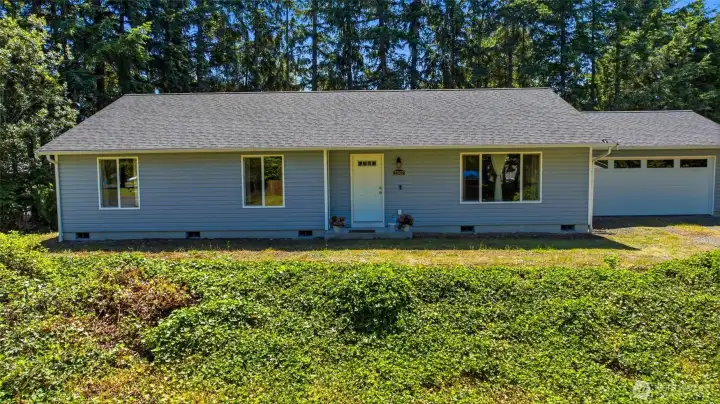 Charming 2012-built rambler with fresh gray lap siding, attached garage, and lush landscaping on a quiet corner lot in Bonney Lake.