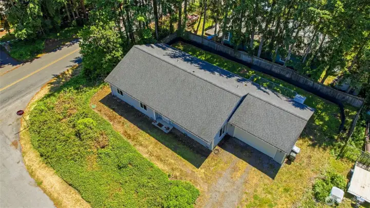 Aerial view of 22022 131st St Ct E — corner lot setting with mature evergreen backdrop and spacious 8,888 sq ft lot.