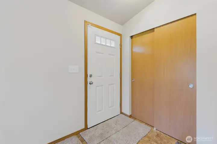 Welcoming entry with craftsman-style front door, transom window, and convenient coat closet — move-in ready.