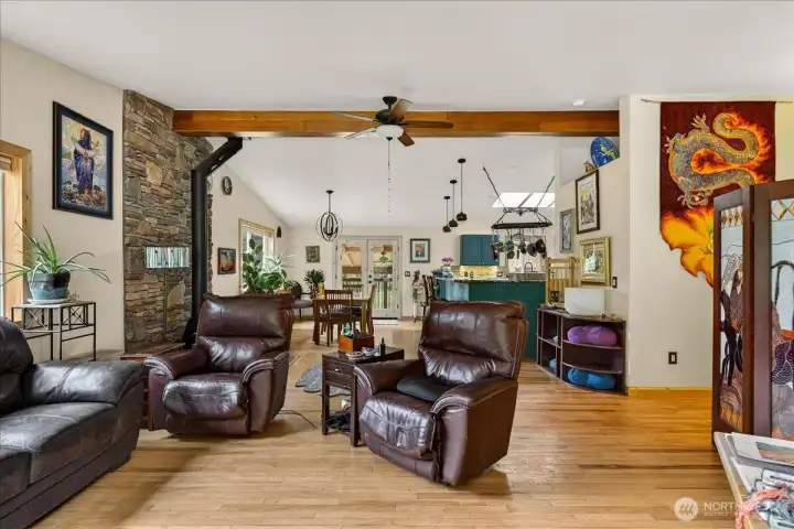 Inviting living room with lots of light, beautiful beam, high end wood stove & open to dining and kitchen.