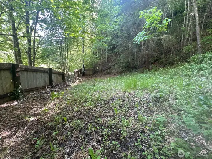 Behind the gate at the base of the hill.