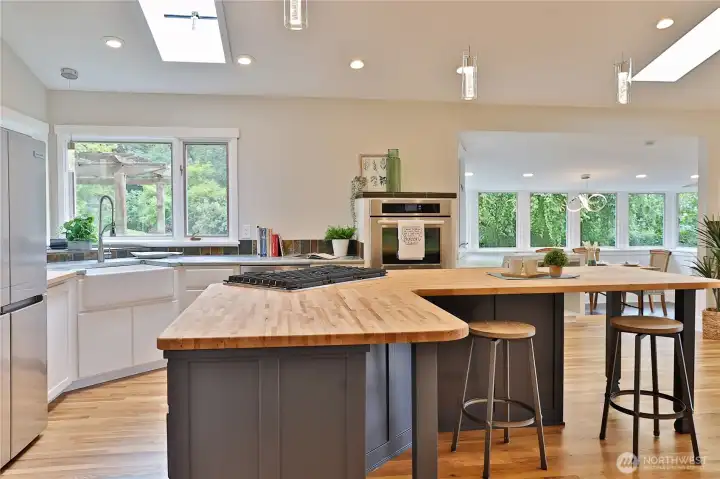 Open kitchen with butcher block counters and refreshed cabinets with new cooktop.