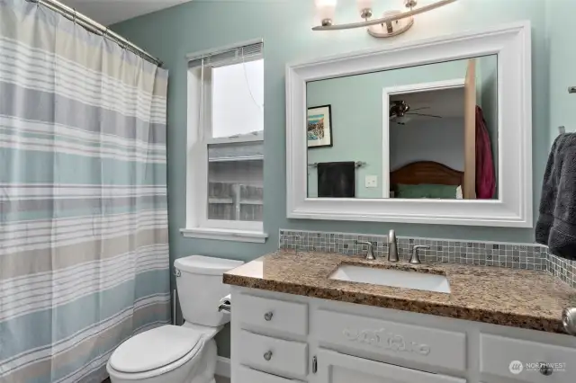 Primary bathroom with tile floors and granite countertop.