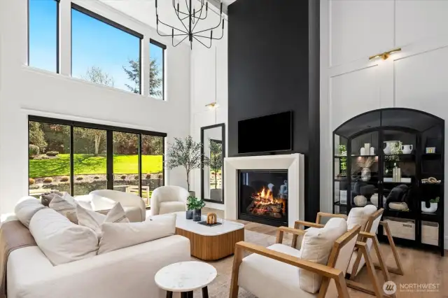 Fireplace in large greatroom, accentlighting; black windows thruought home pronounce the outdoors, views.