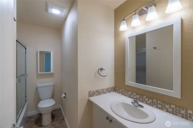 Vanity with lighted mirror and under-counter storage.