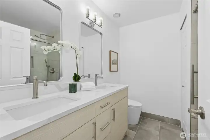 Renovated in 2025, this primary bath features dual vanities, beautiful light fixtures, & custom shower!