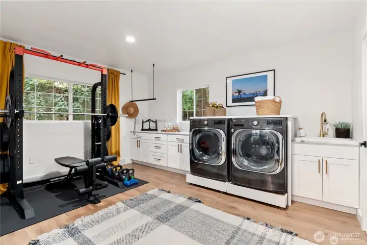 Grand laundry room with a wall of cabinets, utility sink and plenty of space for your private gym!