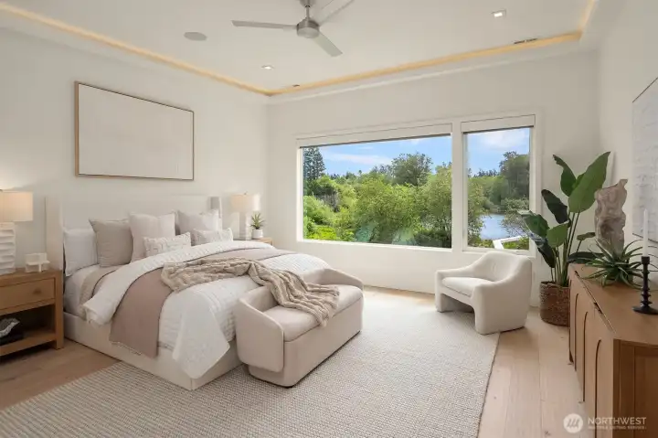 Upper level primary bedroom with cove lighting, ceiling fan, and large windows overlooking the lake. Automated blinds can be controlled from your phone just before you close your eyes!