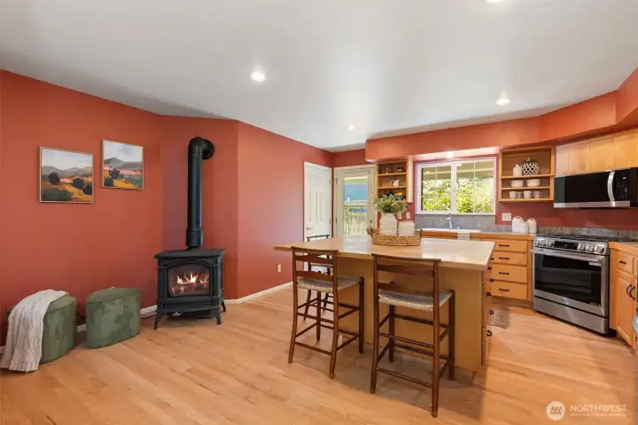 Open kitchen with butcher block island and lots of generous cabinets - another door to the back porch.