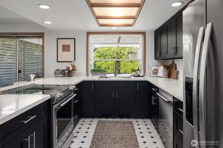 This sleek, updated kitchen is fully equipped and opens to the breakfast bar and family room. A pantry if off to the left unseen.