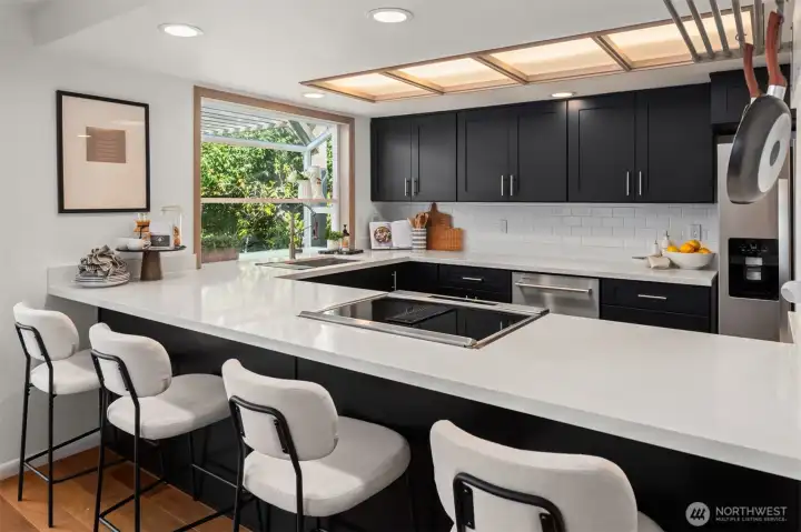 This gorgeous kitchen features quartz counters, tile backsplash and a garden window that looks out over the back deck and yard.