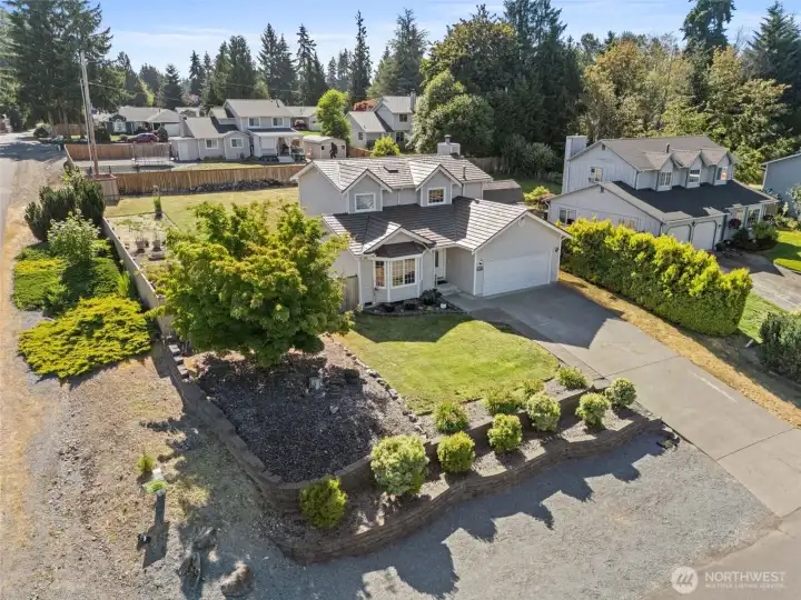 Spacious corner lot with front retaining wall and landscaping. Additional gravel parking off street.