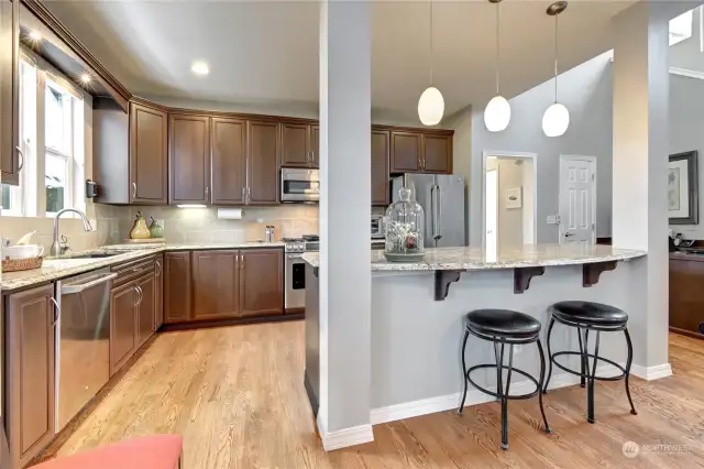 The kitchen features cherry cabinets, slab granite countertops, a generous island with breakfast bar seating and stainless-steel appliances.