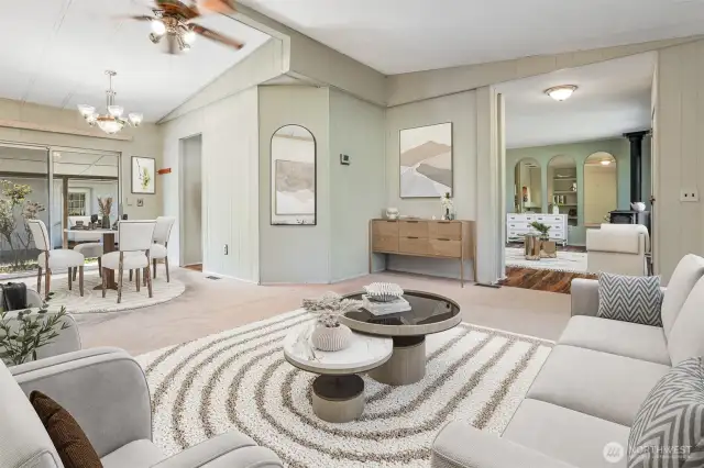 Formal living room with vaulted ceilings overlooks community greenbelt, opens to dining room.  Virtually staged photo.