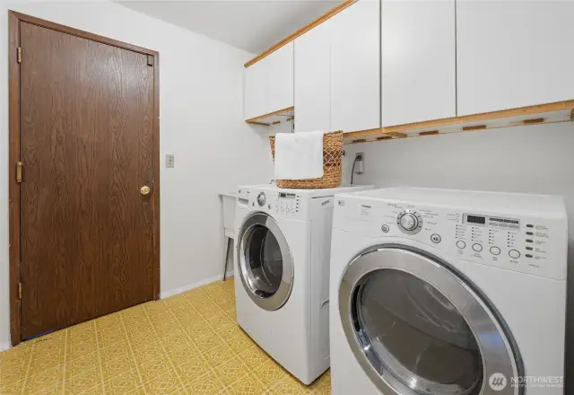 The spacious laundry room is located right off the entry and offers upper cabinet storage, a utility sink, and direct access to the attached two-car garage—making household tasks and unloading a breeze.