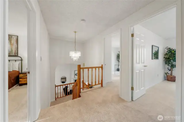 The upper level welcomes you with a view of the additional bedrooms, classic wood detailing, and a beautiful light fixture that adds a touch of charm.