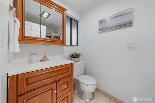 Your Primary Bath features a sleek, glass-enclosed shower, rich wood cabinetry, and a spacious mirrored medicine cabinet—all thoughtfully designed to enhance daily routines with ease and charm.