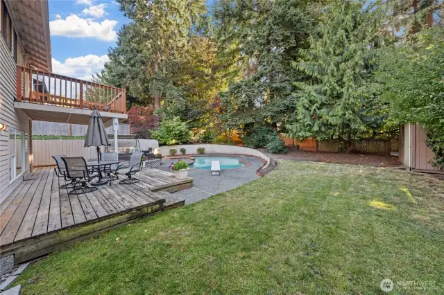 Unwind or entertain on the spacious multi-level deck overlooks the serene pool, surrounded by lush landscaping and tall evergreens!